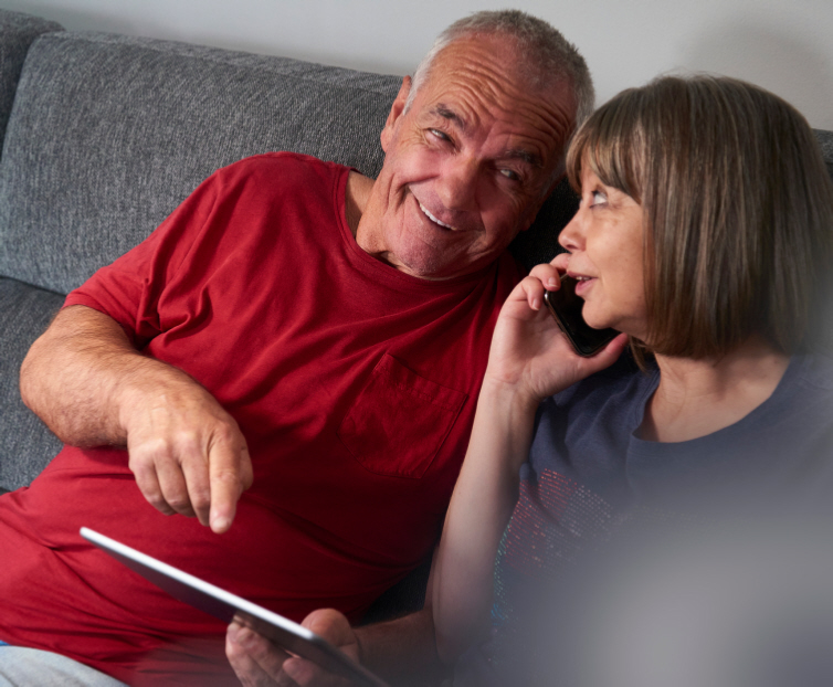 Two people sitting on a sofa. One is talking on the phone