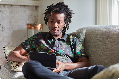 A young man sitting on a sofa looking at a mobile device