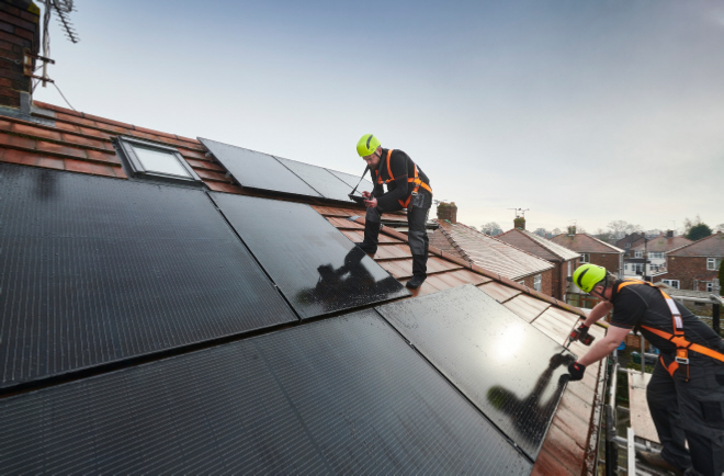 Installers on a roof fitting solar panels